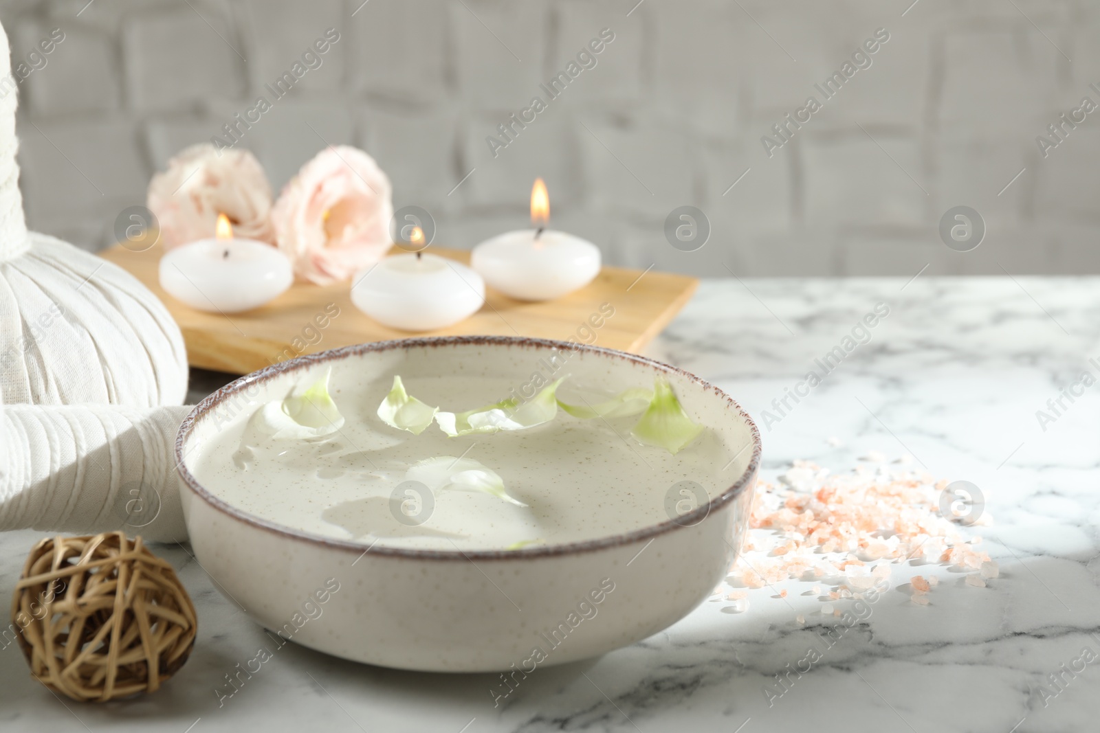 Photo of Spa composition with bowl of water and burning candles on white marble table, closeup