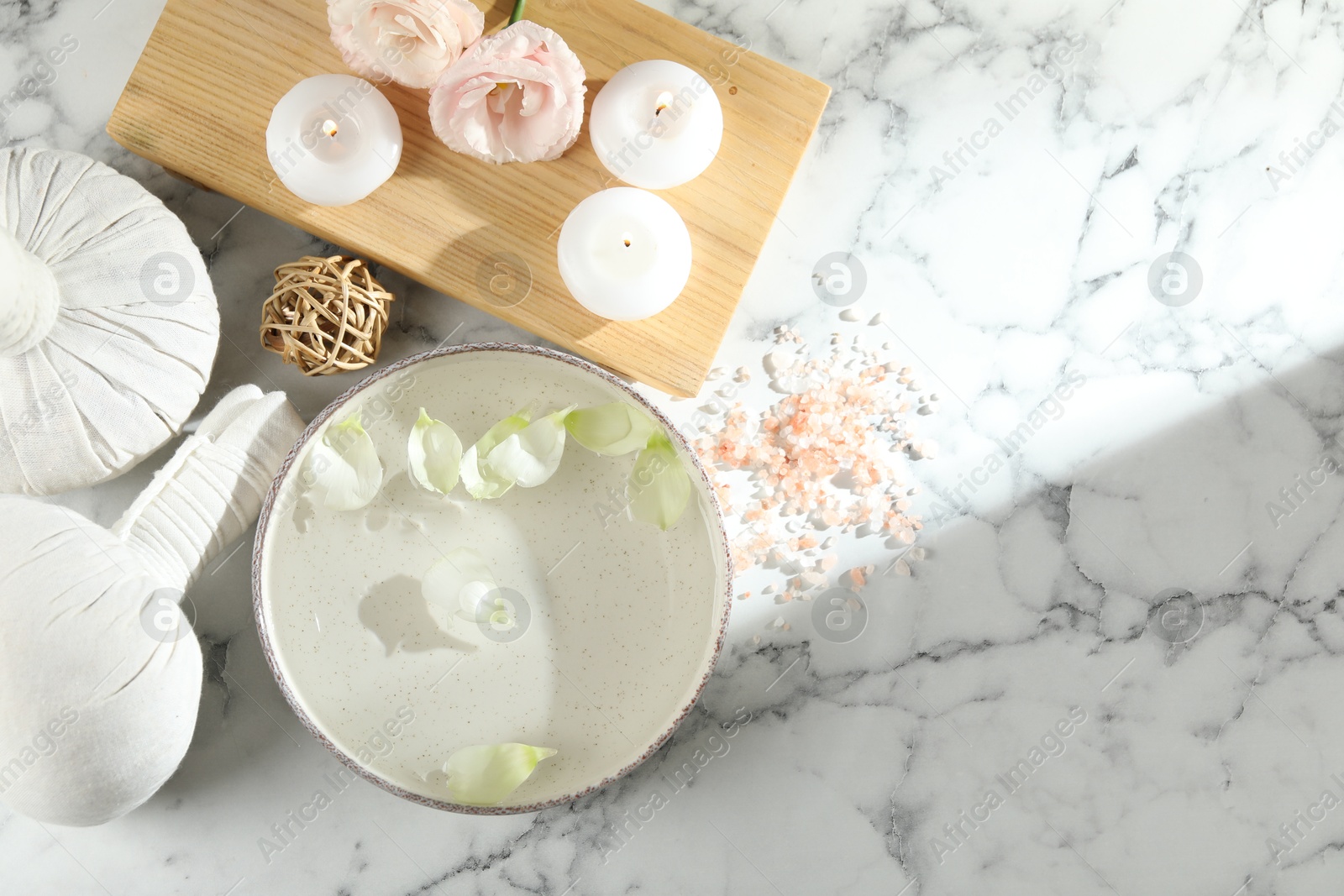 Photo of Spa composition with bowl of water and burning candles on white marble table, flat lay. Space for text