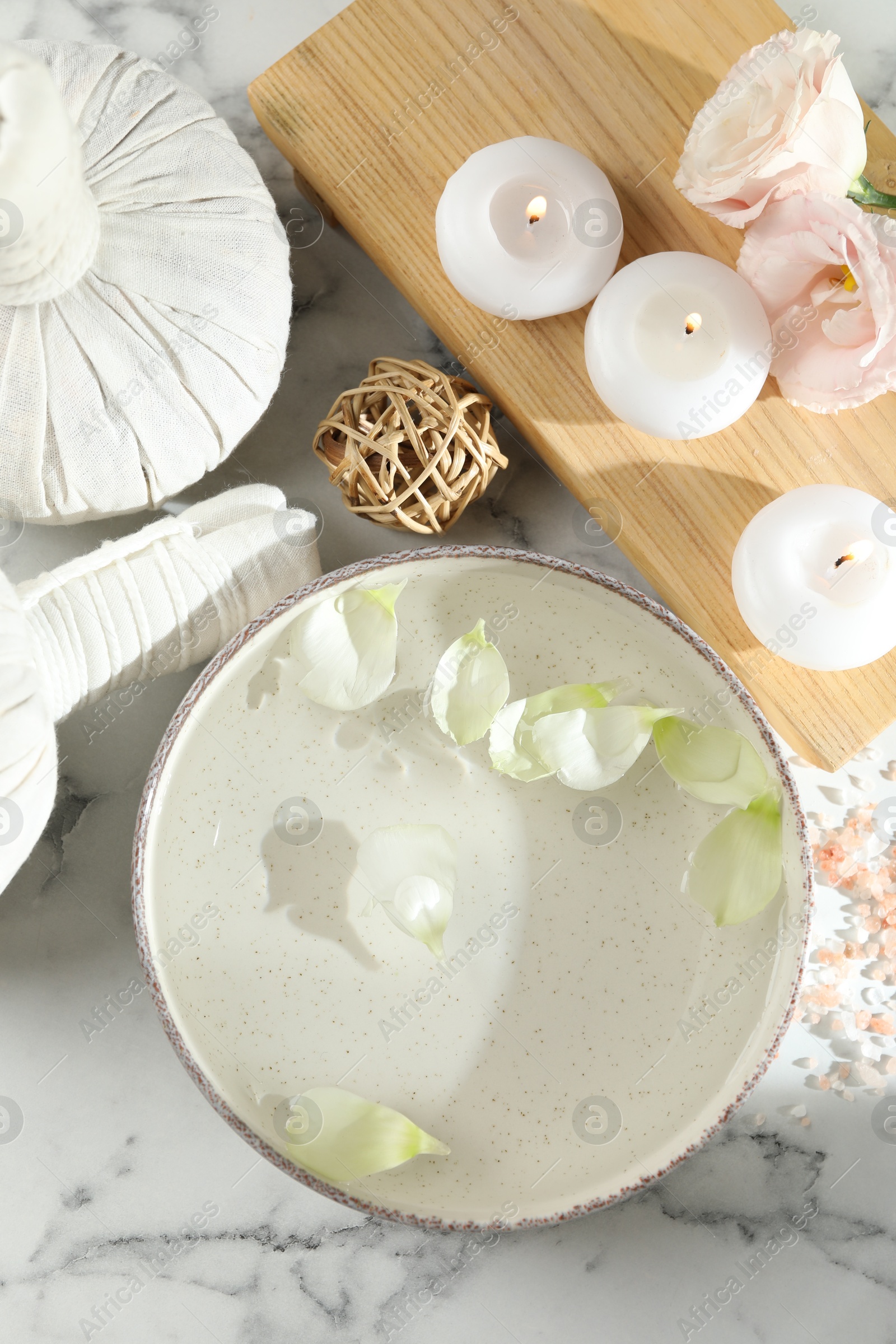 Photo of Spa composition with bowl of water and burning candles on white marble table, flat lay