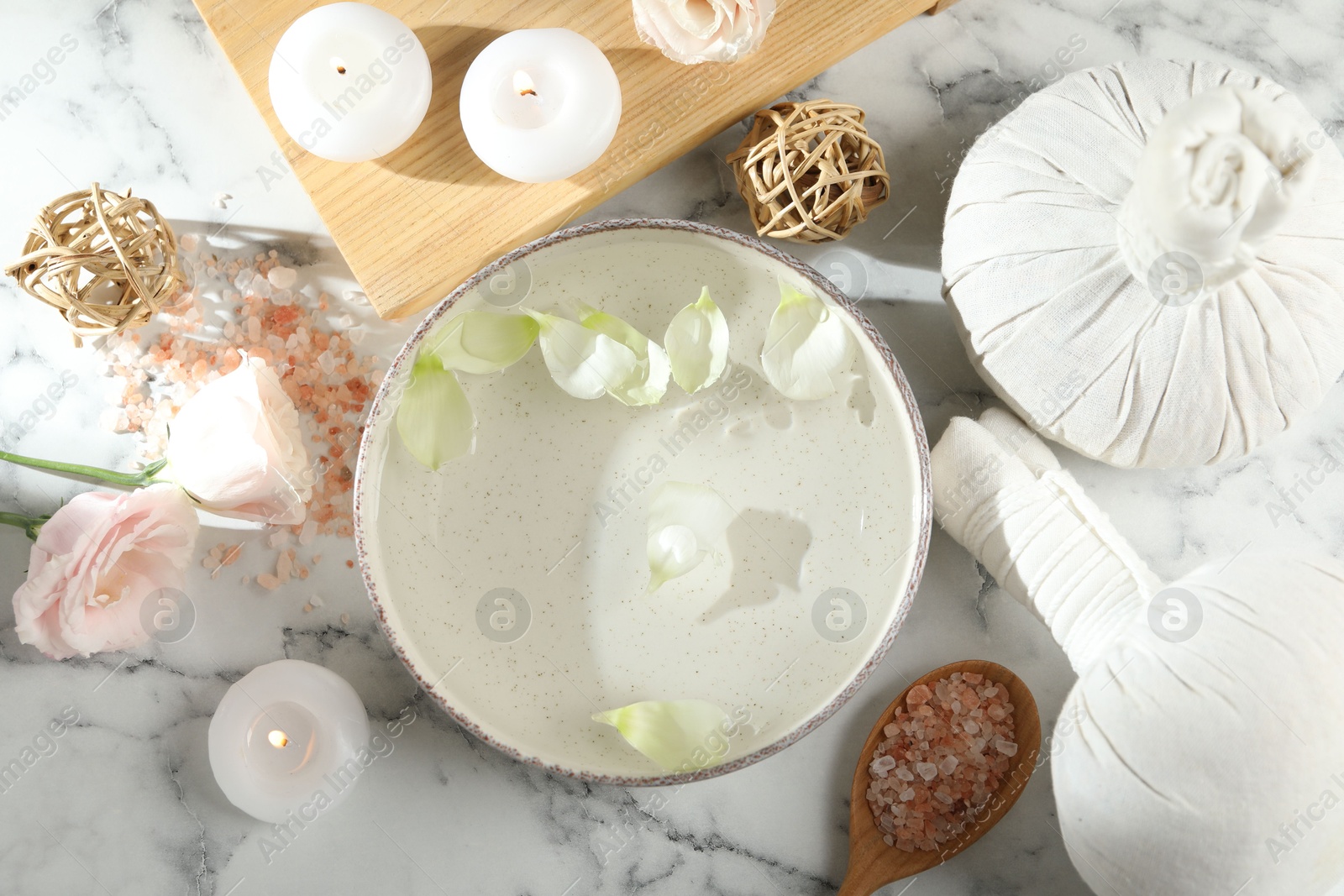 Photo of Spa composition with bowl of water and burning candles on white marble table, flat lay