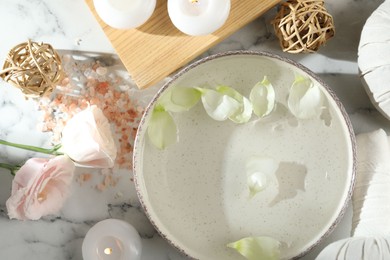 Photo of Spa composition with bowl of water and burning candles on white marble table, flat lay