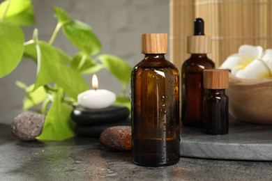 Spa composition with cosmetic products and burning candle on grey table, closeup