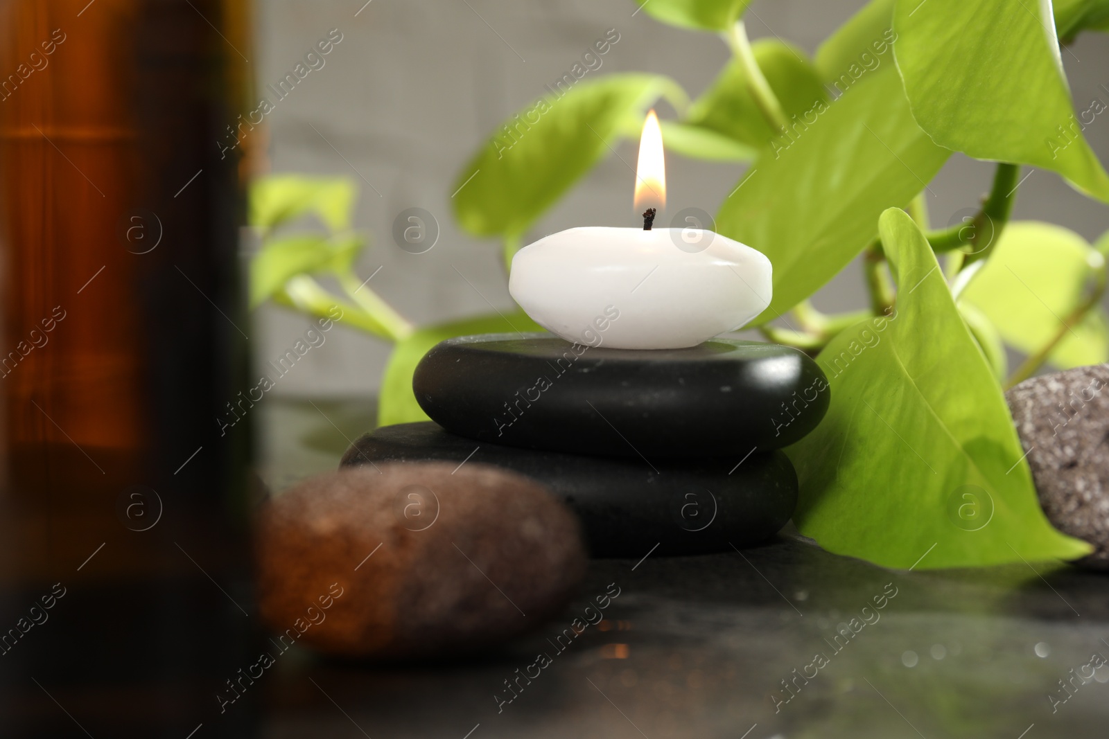 Photo of Spa composition with burning candle on grey table, closeup