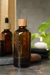 Spa composition with cosmetic products and burning candle on grey table, closeup