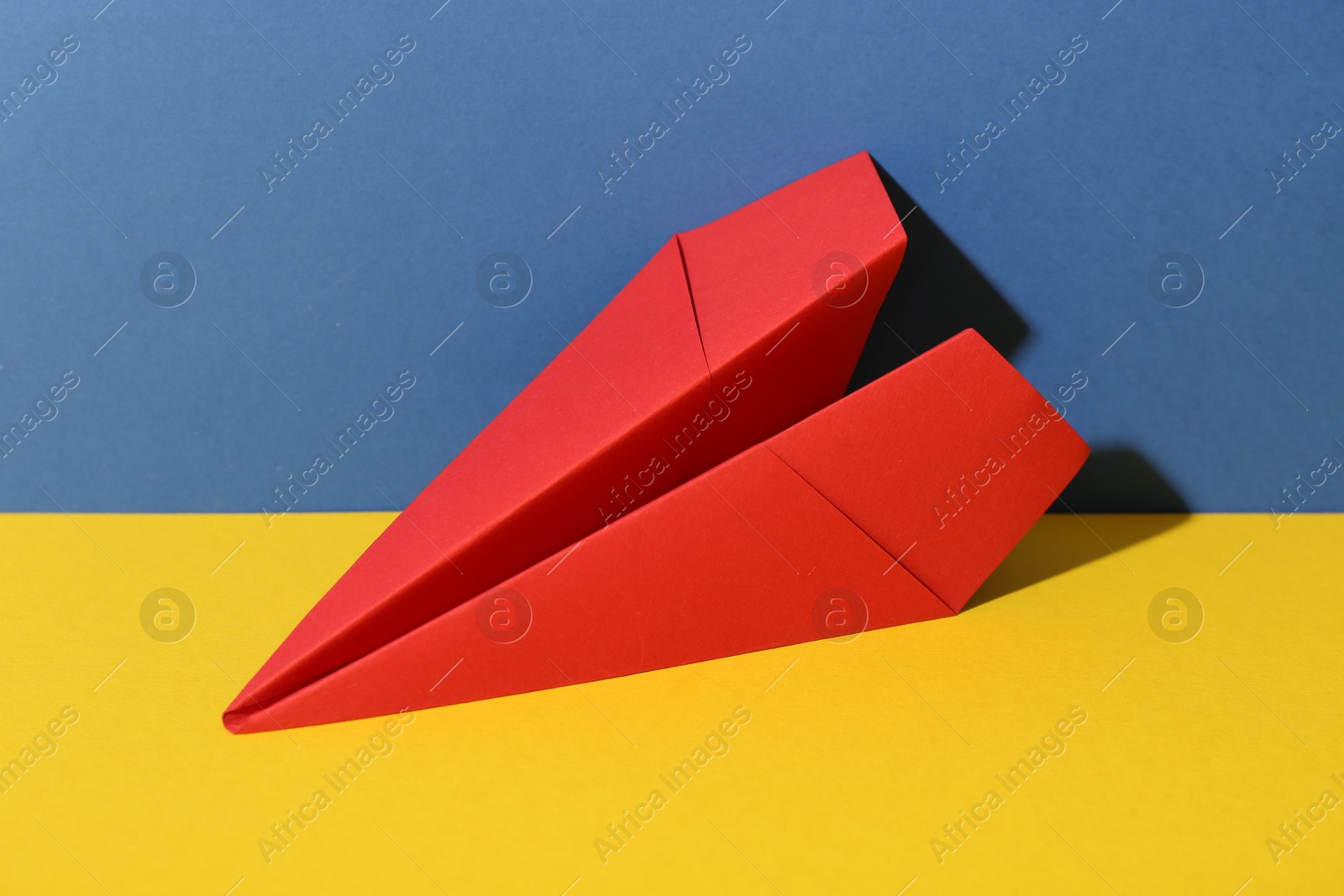 Photo of Handmade red paper plane on color background