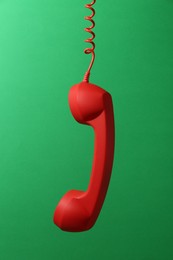 Photo of Red corded telephone handset on green background