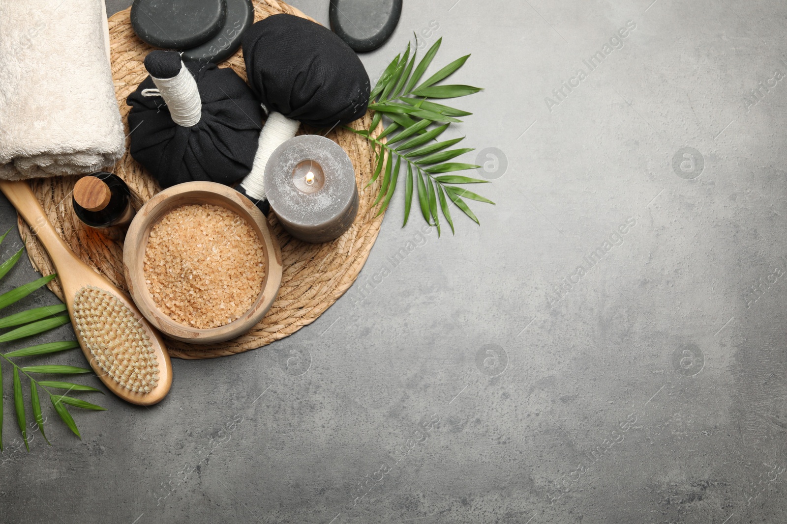 Photo of Spa composition with herbal bags and burning candle on grey table, flat lay. Space for text