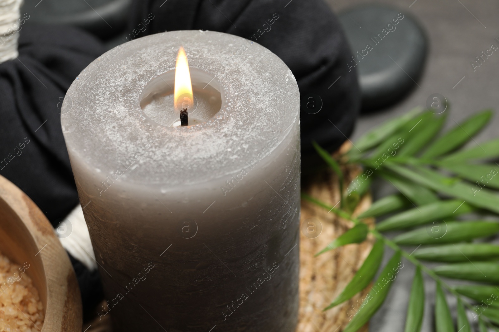 Photo of Spa composition with herbal bags and burning candle on grey table, closeup