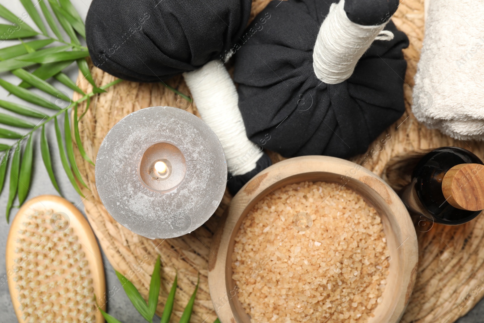 Photo of Spa composition with herbal bags and burning candle on grey table, flat lay