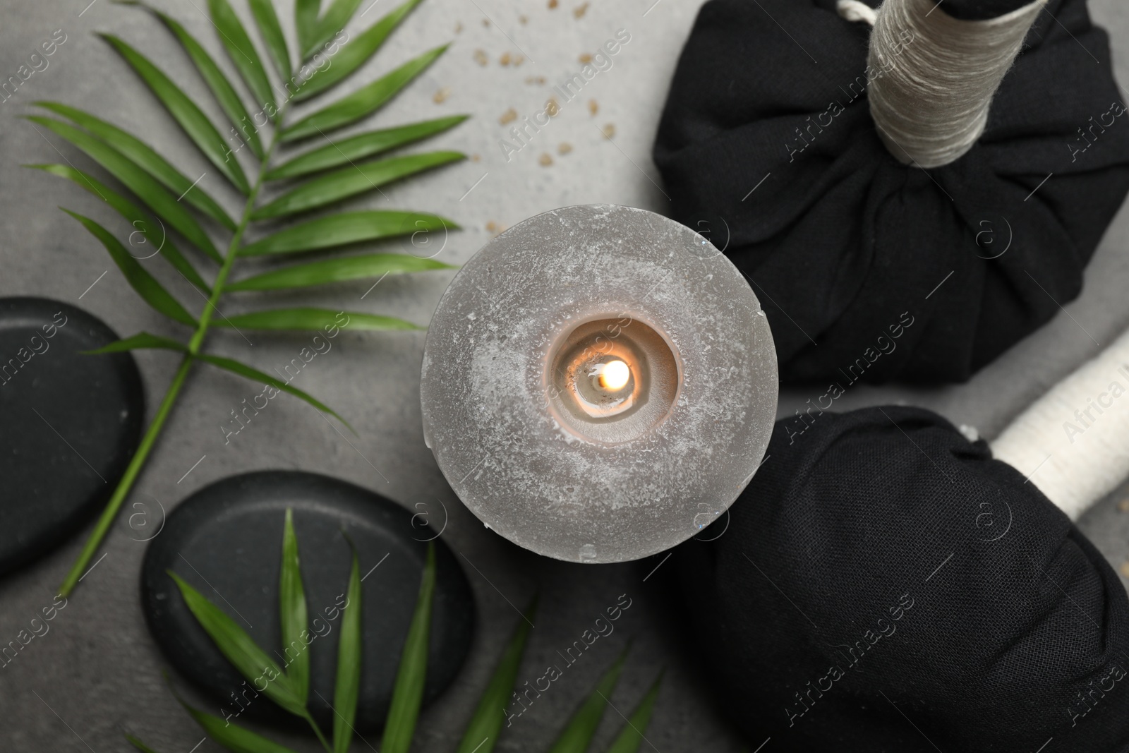 Photo of Spa composition with herbal bags and burning candle on grey table, flat lay