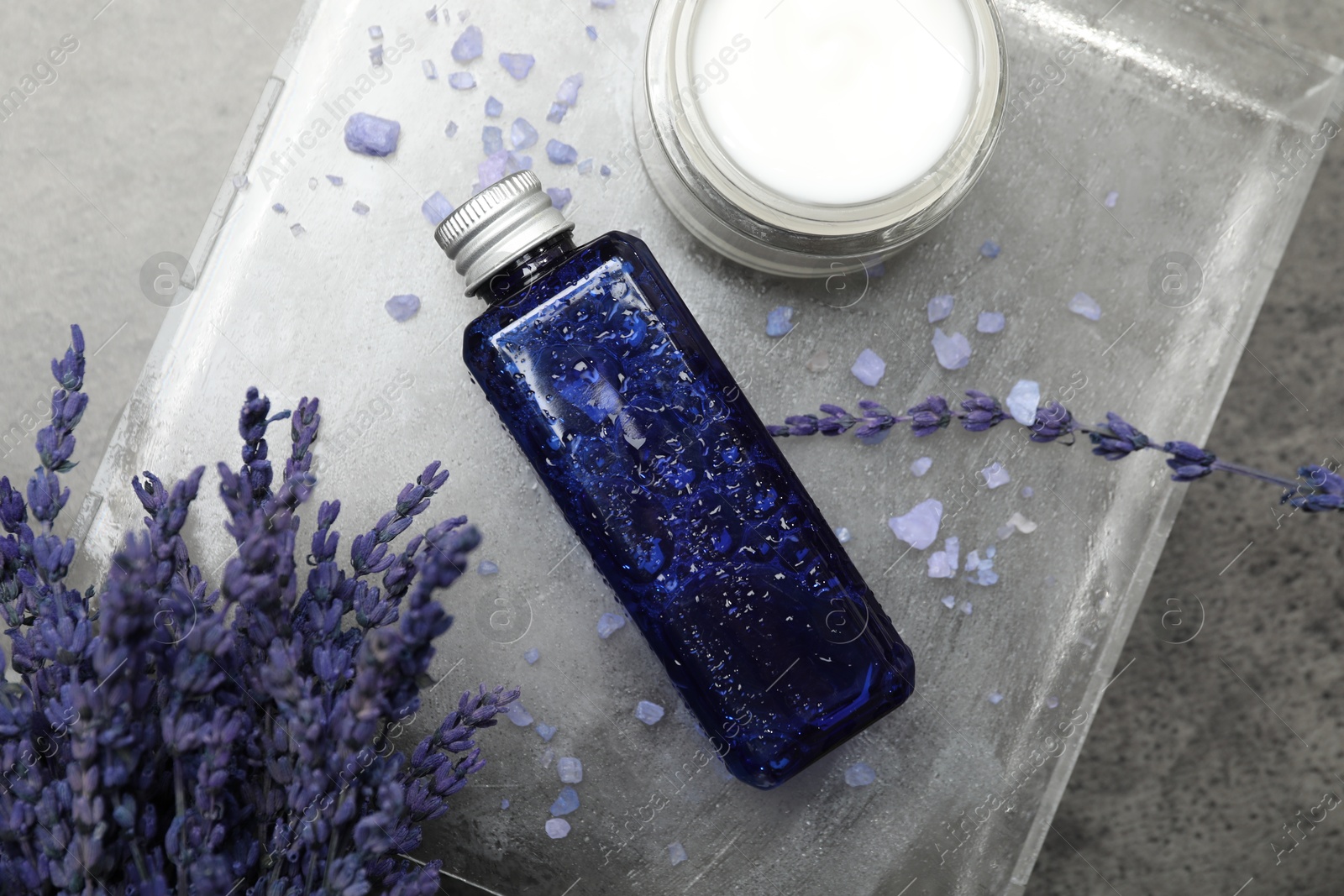 Photo of Spa composition with bottle and jar of cosmetic products on grey table, flat lay