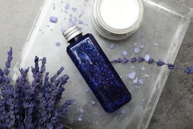 Spa composition with bottle and jar of cosmetic products on grey table, flat lay