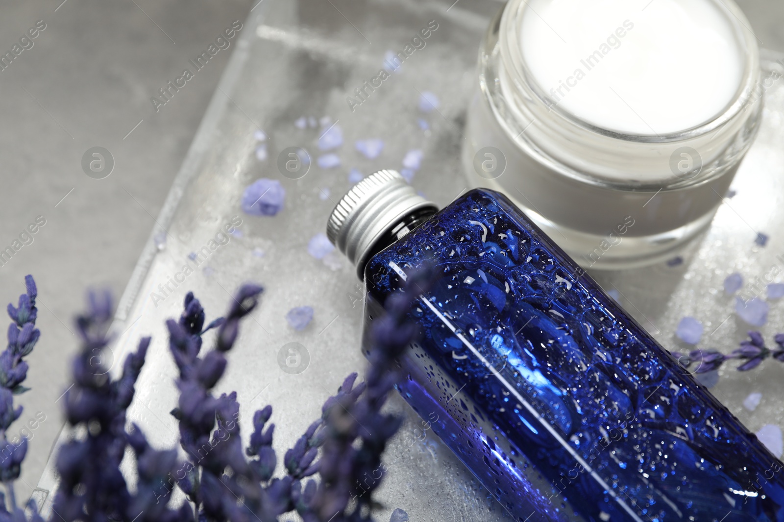 Photo of Spa composition with bottle and jar of cosmetic products on grey table, closeup