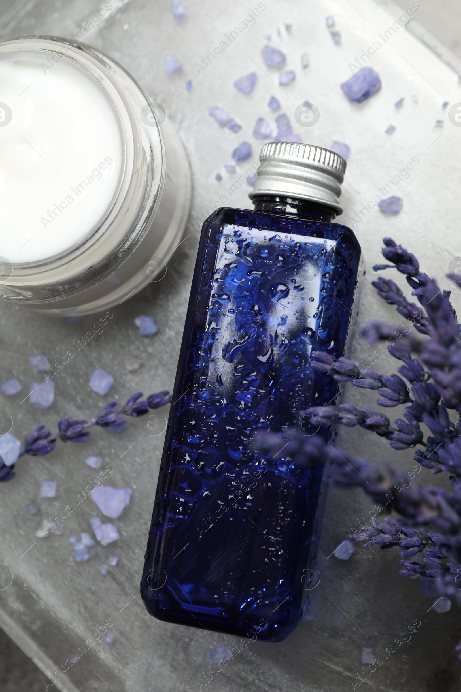 Photo of Spa composition with bottle and jar of cosmetic products on grey table, flat lay