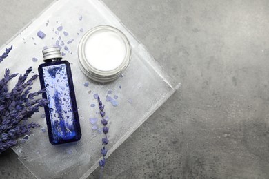 Spa composition with bottle and jar of cosmetic products on grey table, flat lay. Space for text