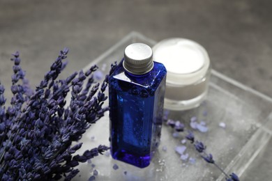 Spa composition with bottle and jar of cosmetic products on grey table