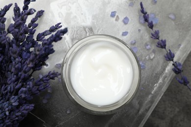 Photo of Spa composition with jar of cosmetic product and lavender flowers on grey table, flat lay