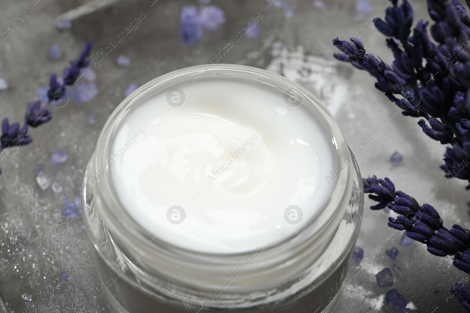 Photo of Spa composition with jar of cosmetic product and lavender flowers on grey table, closeup