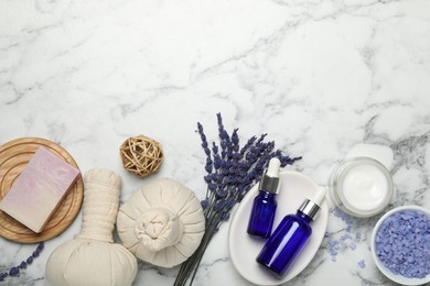 Photo of Spa composition with different cosmetic products, herbal bags and lavender flowers on white marble table, flat lay