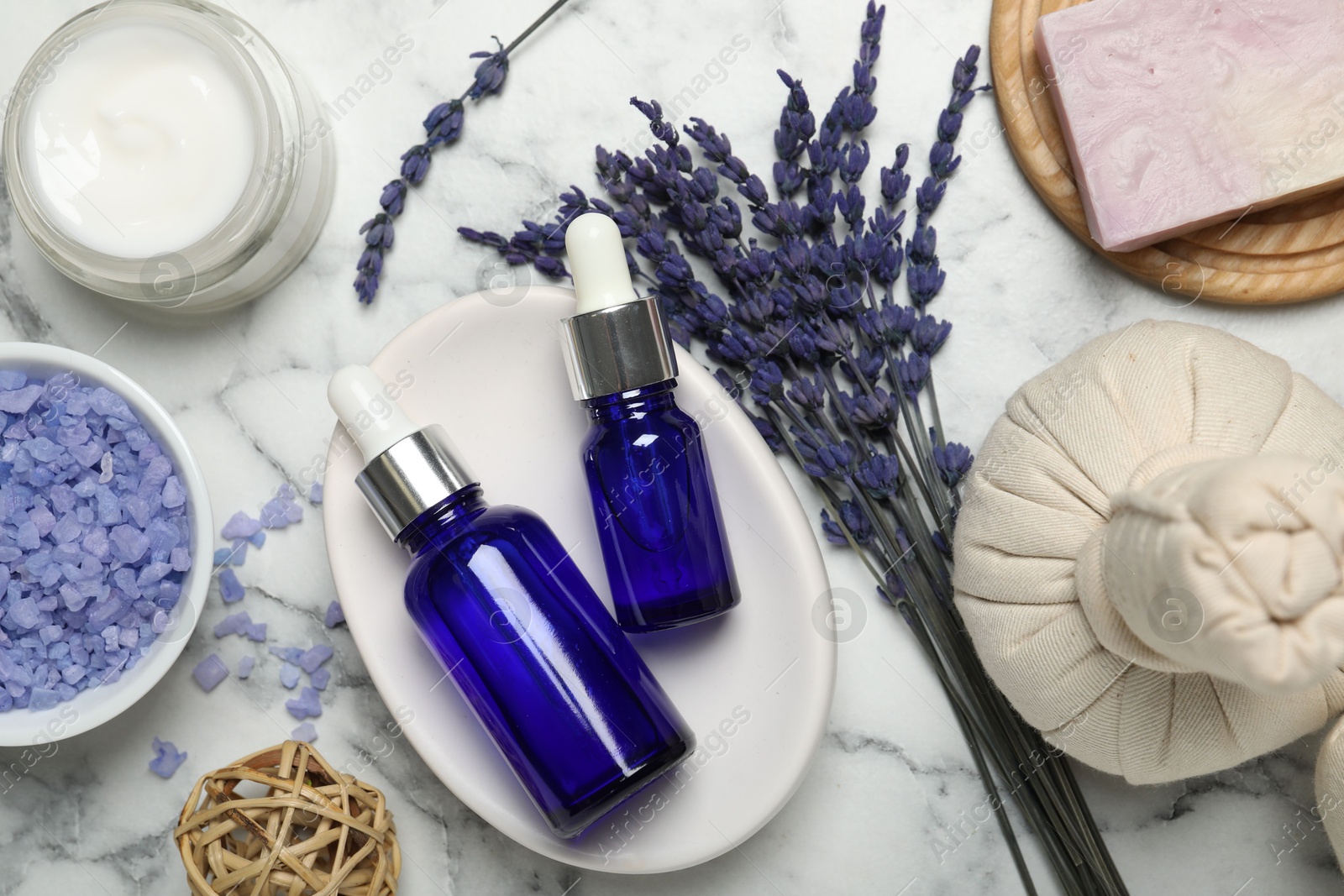 Photo of Spa composition with different cosmetic products, herbal bags and lavender flowers on white marble table, flat lay