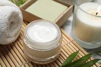 Photo of Spa composition with different cosmetic products, burning candle and leaves on white marble table, closeup