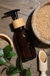 Spa composition with sea salt, bottle of cosmetic product and leaves on wooden table, flat lay