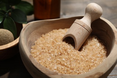 Bowl with sea salt and leaves on wooden table, closeup. Spa treatment