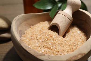 Bowl with sea salt and leaves on wooden table, closeup. Spa treatment