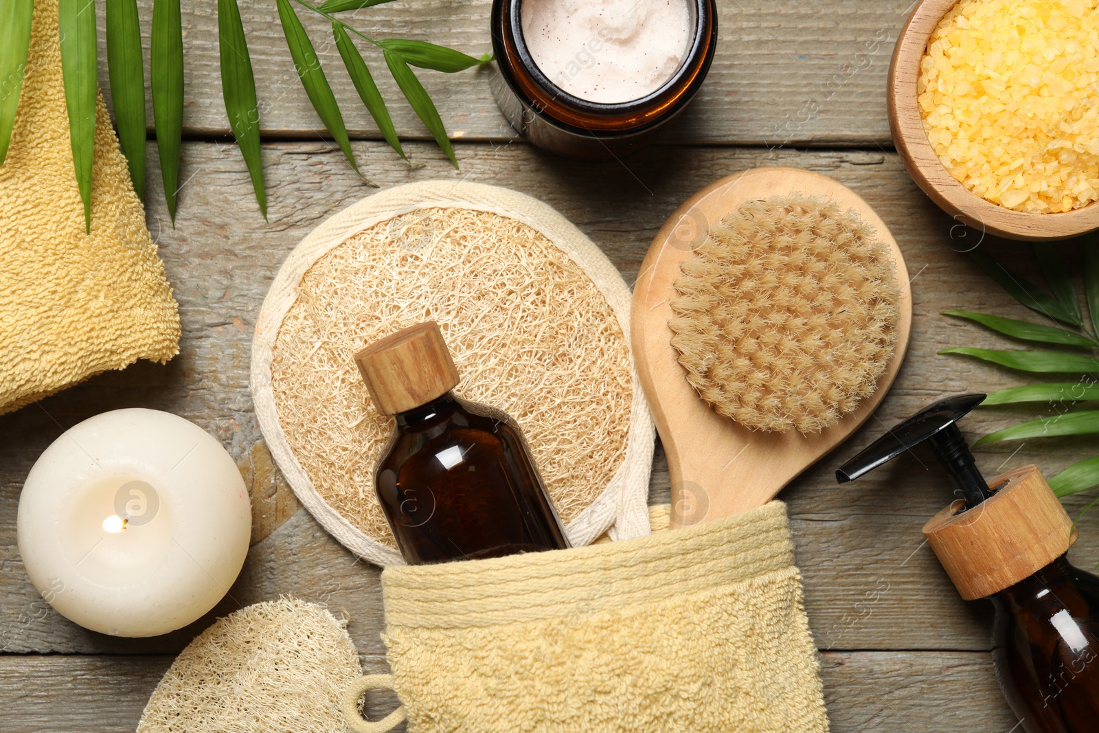 Photo of Spa composition with different cosmetic products and burning candle on wooden table, flat lay