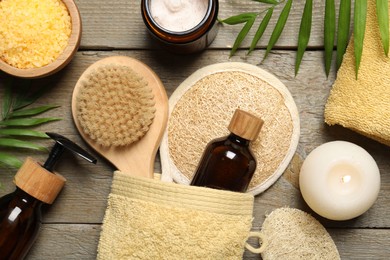 Photo of Spa composition with different cosmetic products and burning candle on wooden table, flat lay