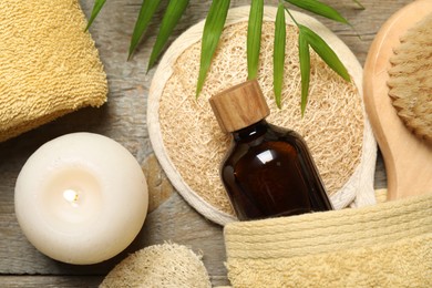 Spa composition with different cosmetic products and burning candle on wooden table, flat lay