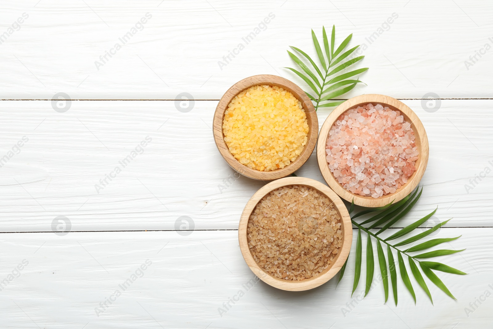 Photo of Spa composition with different types of sea salt on white wooden table, flat lay. Space for text