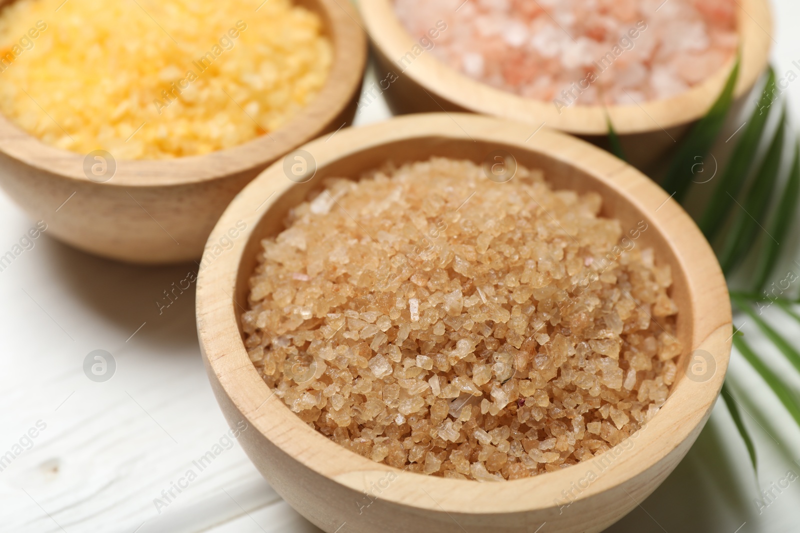 Photo of Spa composition with different types of sea salt on white wooden table, closeup