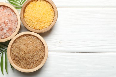 Spa composition with different types of sea salt on white wooden table, flat lay. Space for text