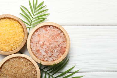 Spa composition with different types of sea salt on white wooden table, flat lay. Space for text