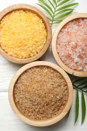 Spa composition with different types of sea salt on white wooden table, flat lay