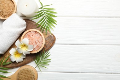 Photo of Spa composition with sea salt, plumeria flowers and burning candle on white wooden table, flat lay. Space for text