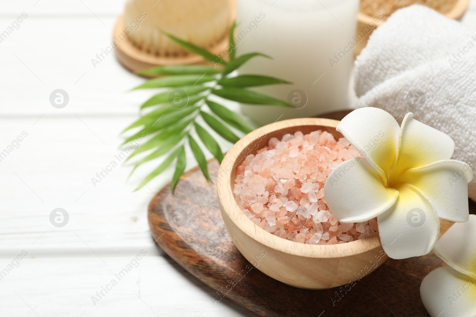 Photo of Spa composition with sea salt, plumeria flowers and burning candle on white wooden table, closeup. Space for text