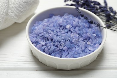 Photo of Bowl with sea salt, towel and lavender flowers on white wooden table. Spa treatment