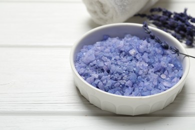 Bowl with sea salt, towel and lavender flowers on white wooden table. Spa treatment