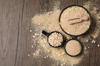 Photo of Oat bran and flakes on wooden table, flat lay. Space for text