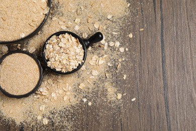 Photo of Oat bran and flakes on wooden table, flat lay. Space for text