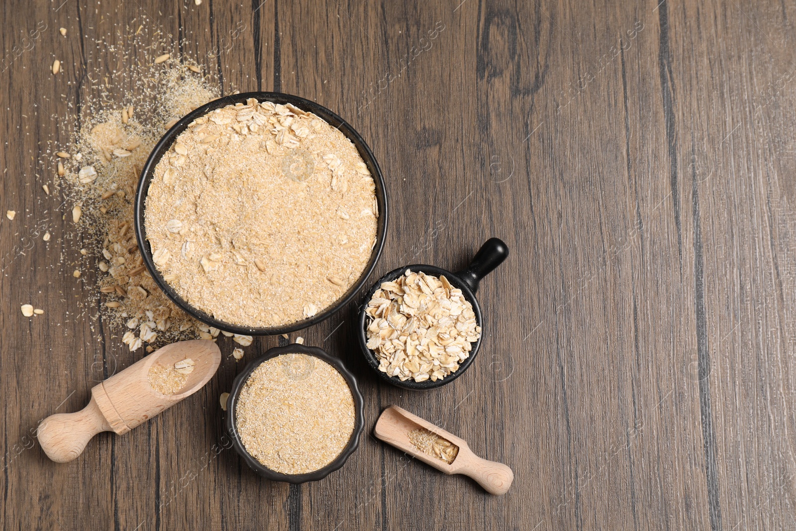 Photo of Oat bran and flakes on wooden table, flat lay. Space for text