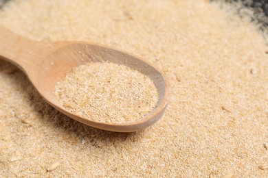 Photo of Pile of oat bran and wooden spoon on table, closeup