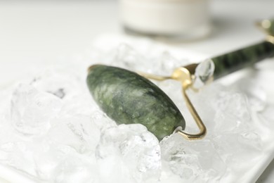 Photo of Face roller and ice cubes on white table, closeup