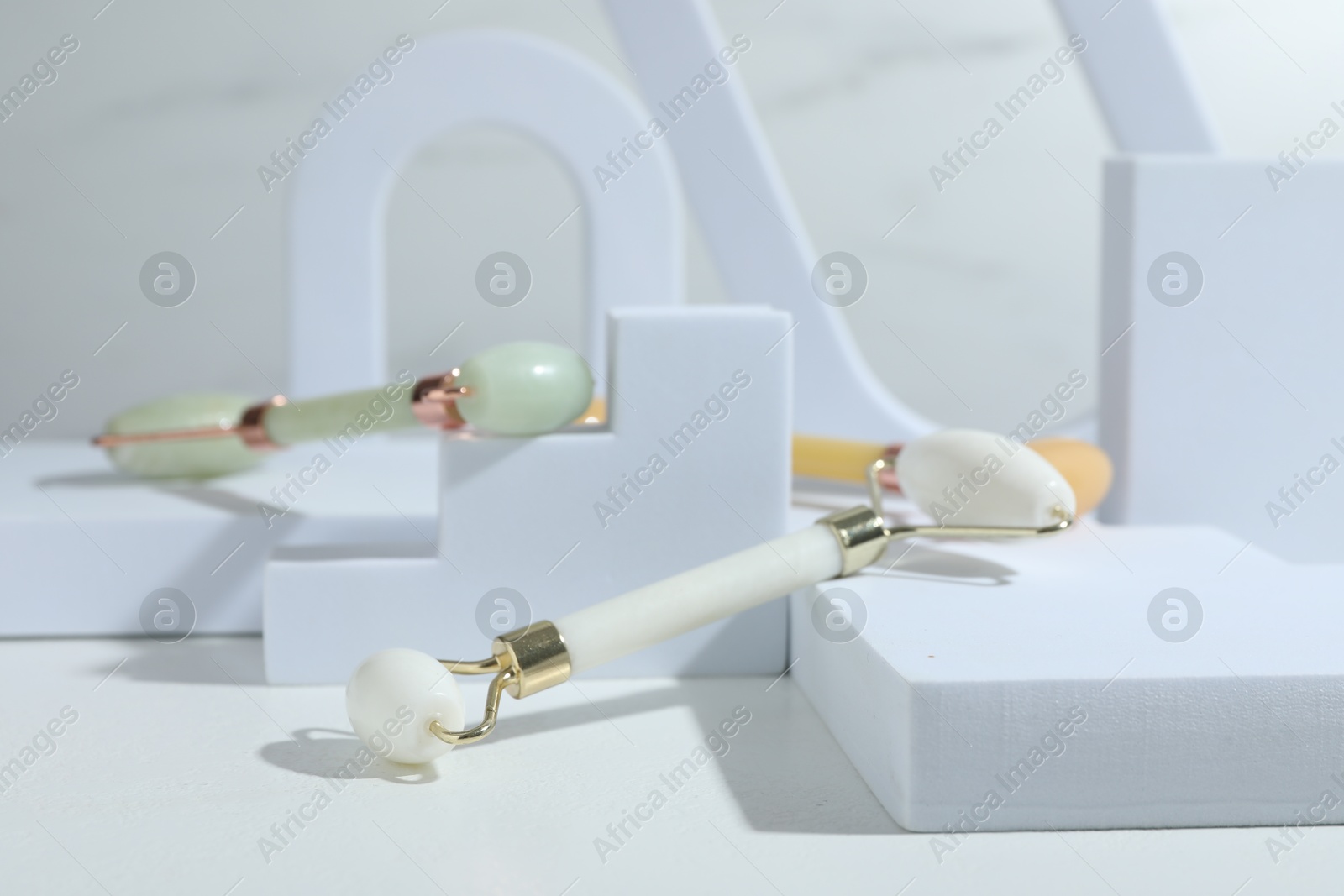 Photo of Stylish presentation of face rollers on light grey background, closeup