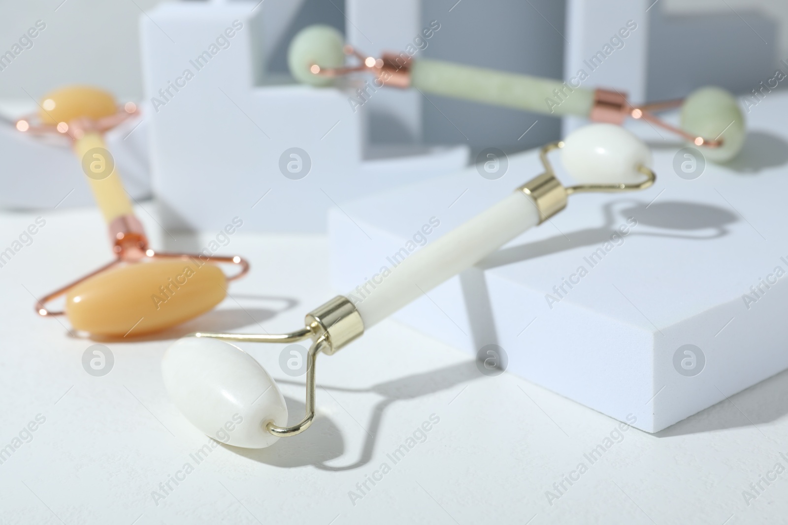 Photo of Stylish presentation of face rollers on light grey background, closeup