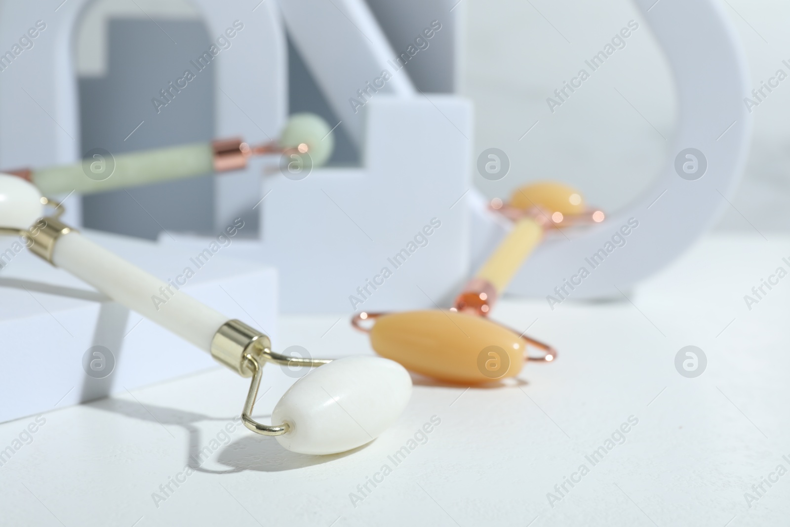 Photo of Stylish presentation of face rollers on light grey background, closeup