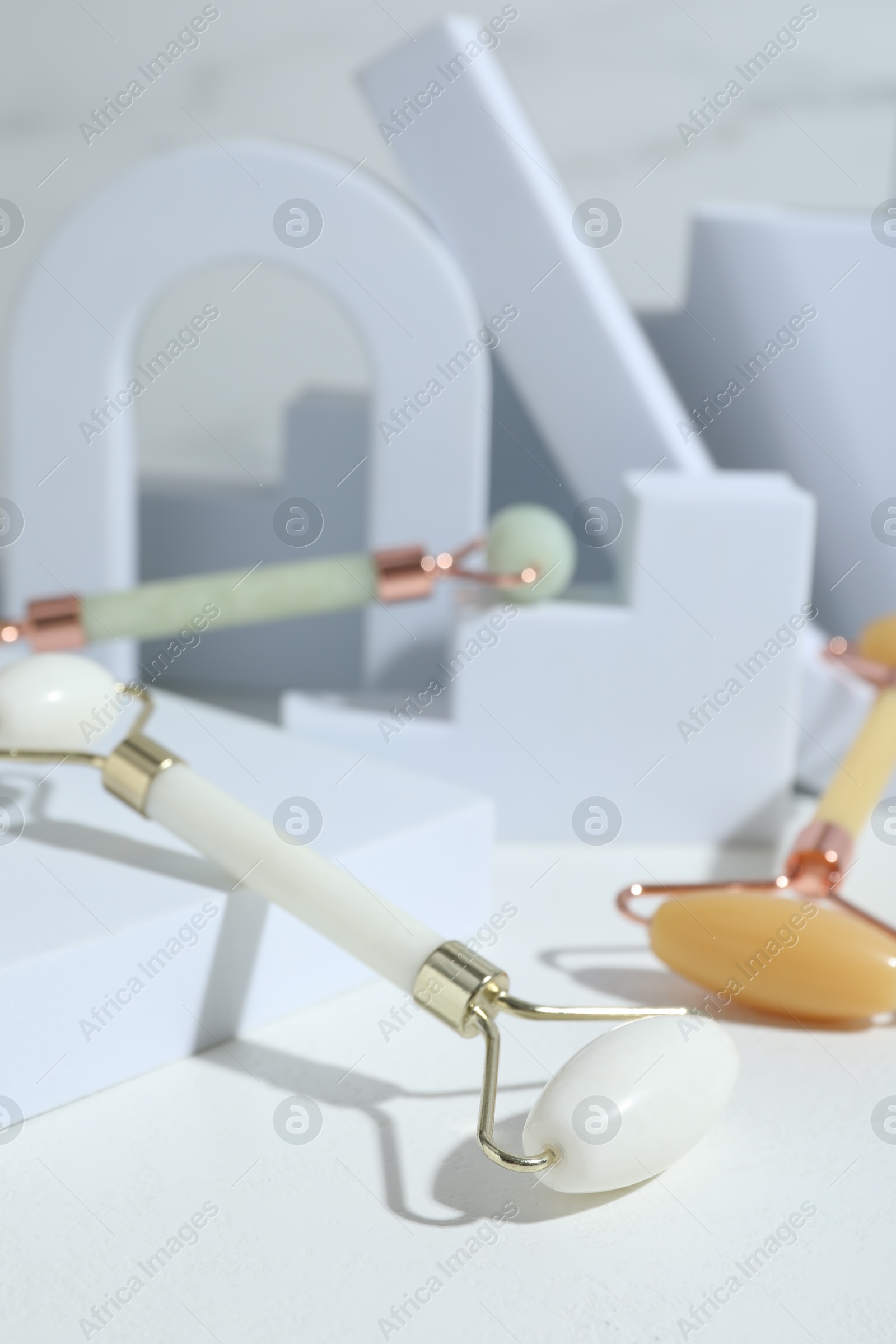 Photo of Stylish presentation of face rollers on light grey background, closeup