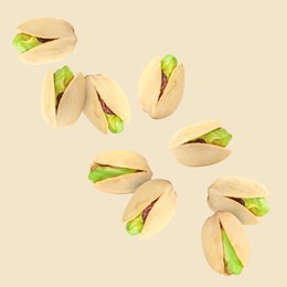 Tasty pistachios in air on color background